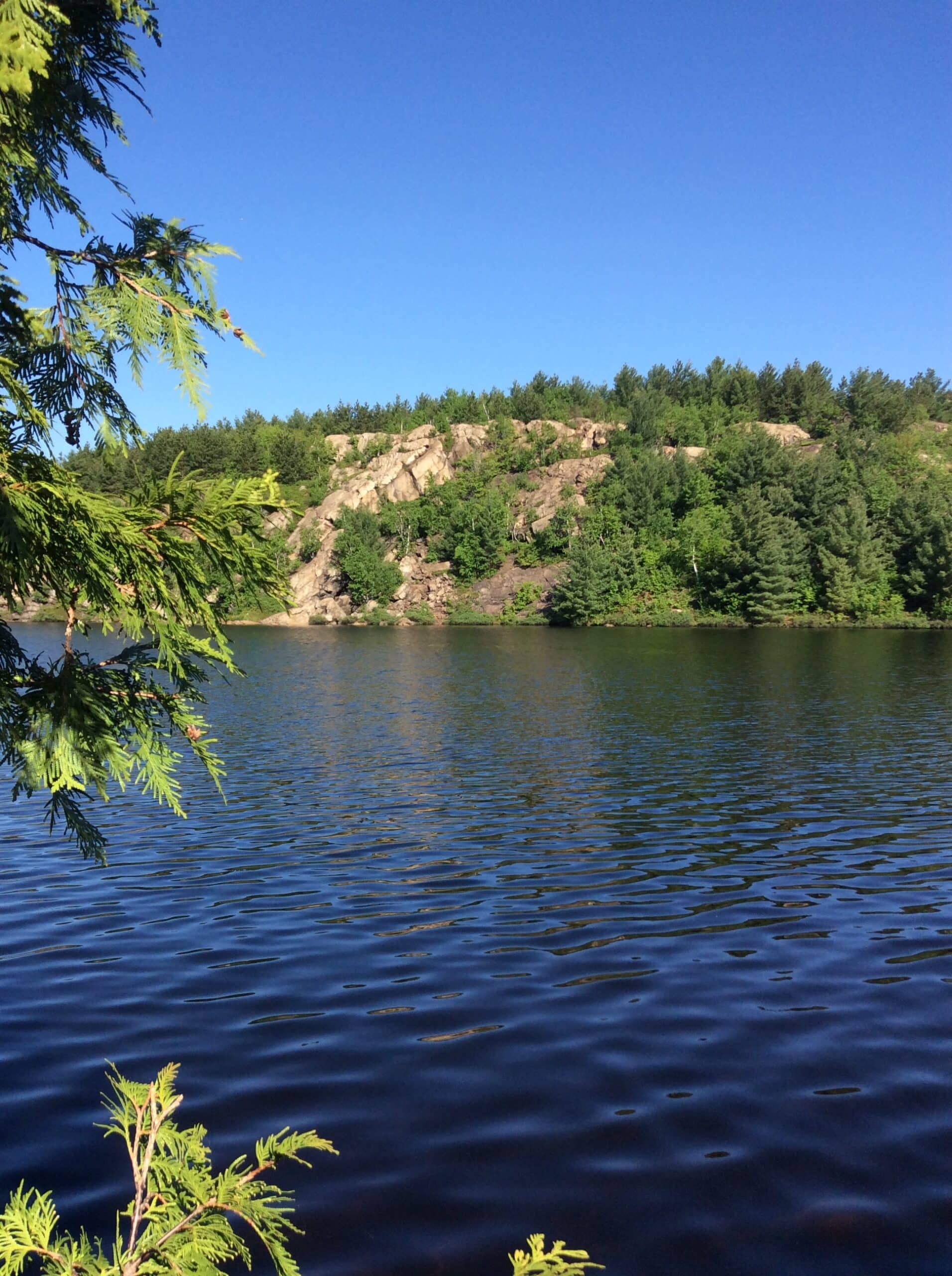 Photo du lac entouré de collines rocheuses et d'arbres